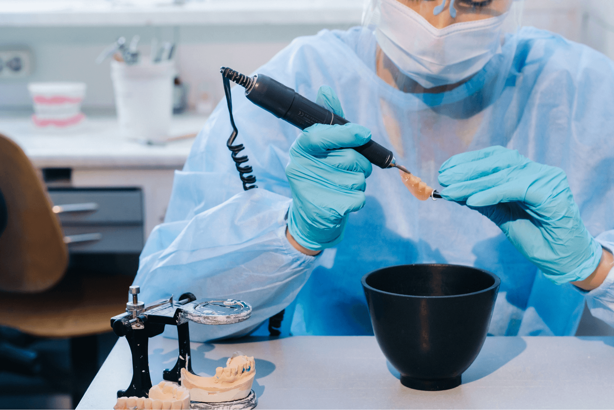 Bild in Großformat: Eine Person in blauen Handschuhen hält ein Werkzeug über einer schwarzen Schüssel.