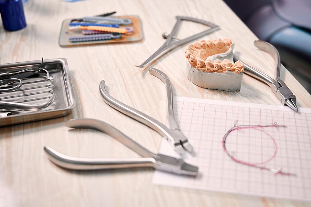 Tisch mit dentaltechnischen Instrumenten, welches ein Gebissmodell restauriert.